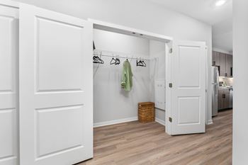 A white closet with a basket and clothes hanging on a rail.